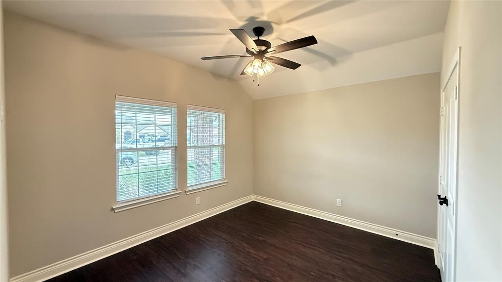 704 Ransom Way Greenville, TX 75402 - Photo 11 of 23 Spare room with dark wood-style flooring, vaulted ceiling, and a ceiling fan