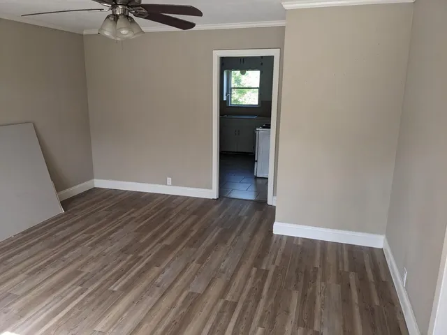 a view of a room with wooden floor a ceiling fan and window