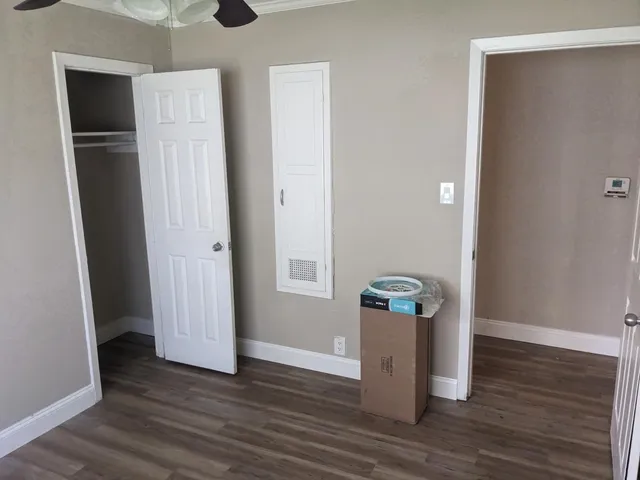 a view of an empty room with wooden floor and closet