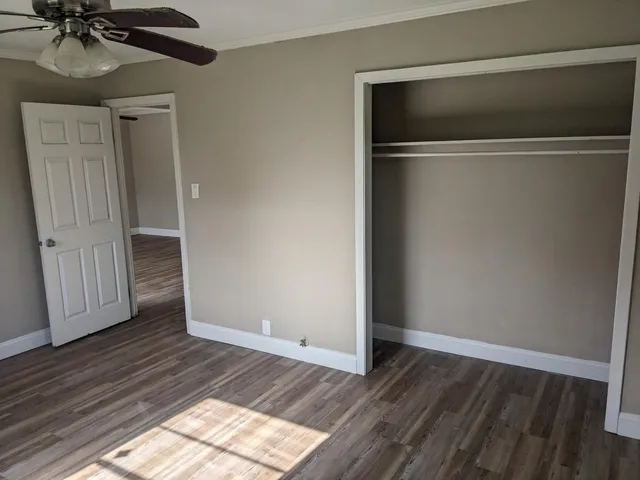 a view of an empty room with a window and wooden floor