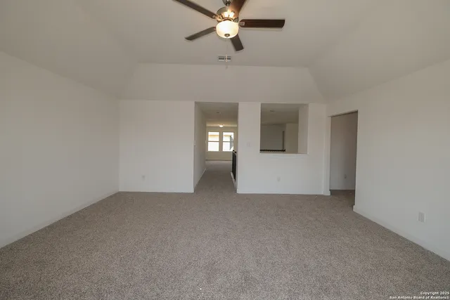 an empty room with chandelier fan and windows