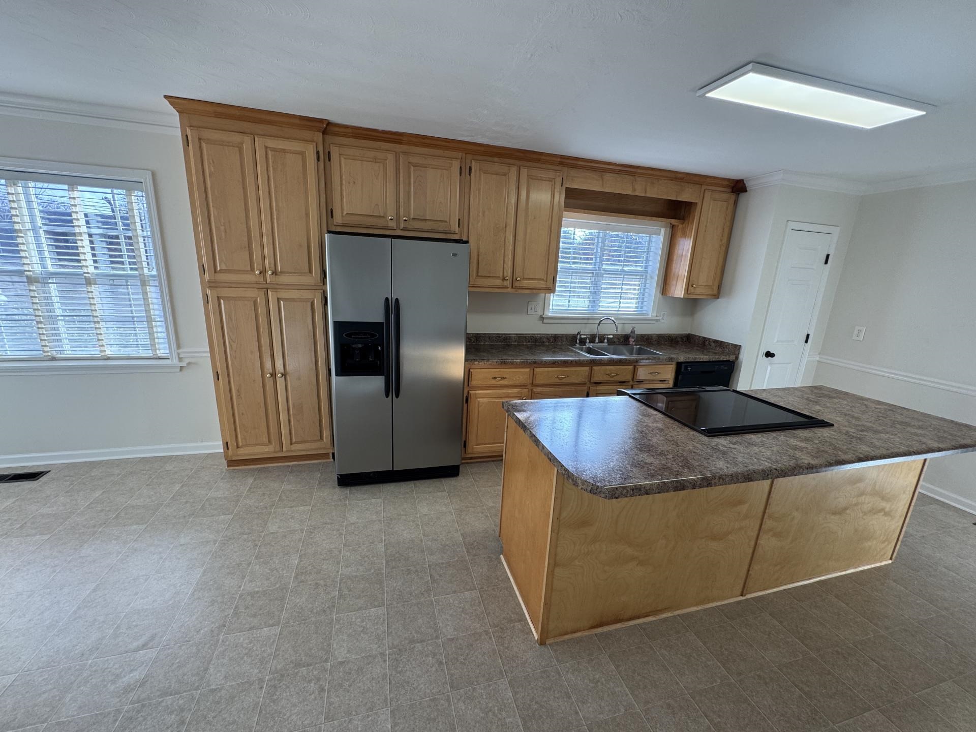 2823 Elmore Park Road Bartlett, TN 38134 - Photo 5 of 22 Kitchen featuring stainless steel refrigerator with ice dispenser, dark countertops, crown molding, a center island, and wood finish cabinetry