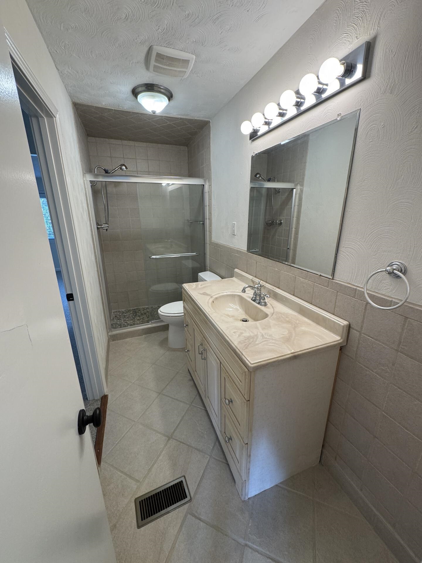 2823 Elmore Park Road Bartlett, TN 38134 - Photo 8 of 22 Bathroom featuring vanity, a stall shower, a textured ceiling, tile walls, and light tile patterned floors