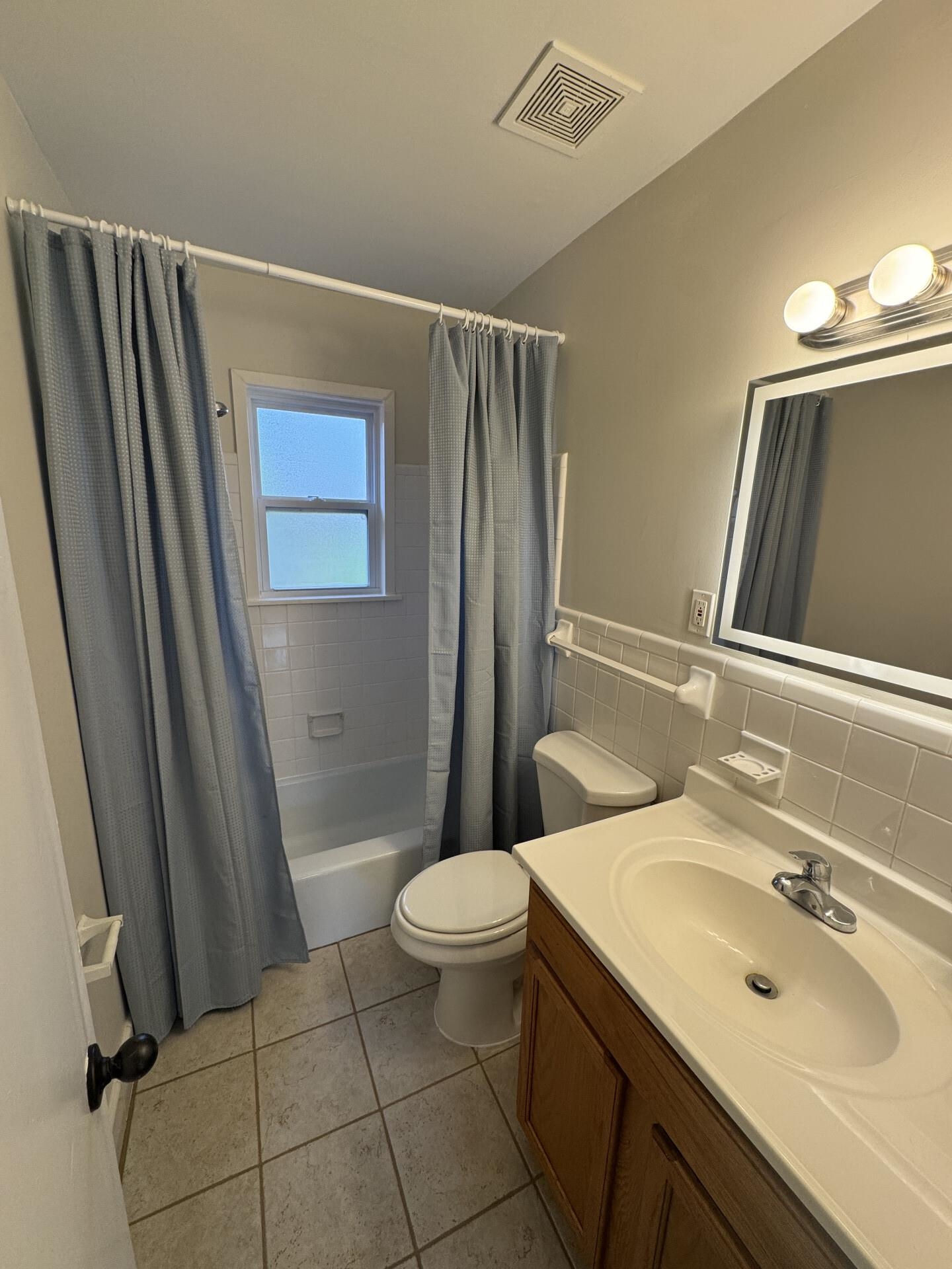 2823 Elmore Park Road Bartlett, TN 38134 - Photo 10 of 22 Bathroom with vanity, shower / bath combination with curtain, tile walls, a wainscoted wall, and light tile patterned floors