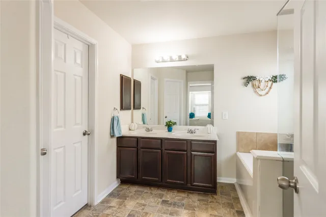 a bathroom with a double vanity sink mirror and bathtub