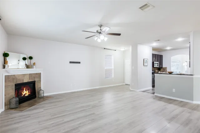 a view of an empty room with kitchen and fireplace