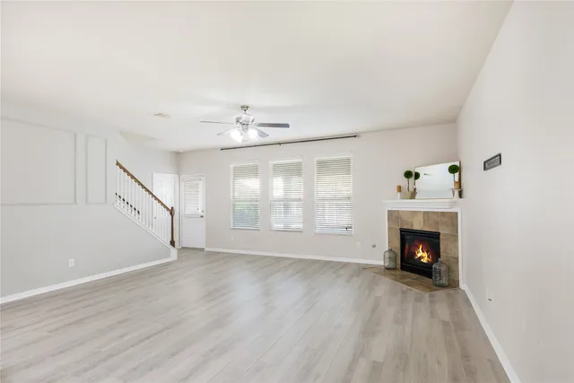 a view of an empty room with wooden floor fireplace and a window