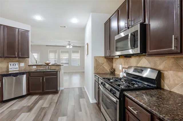 a kitchen with stainless steel appliances granite countertop a stove top oven a sink dishwasher and microwave oven with cabinets