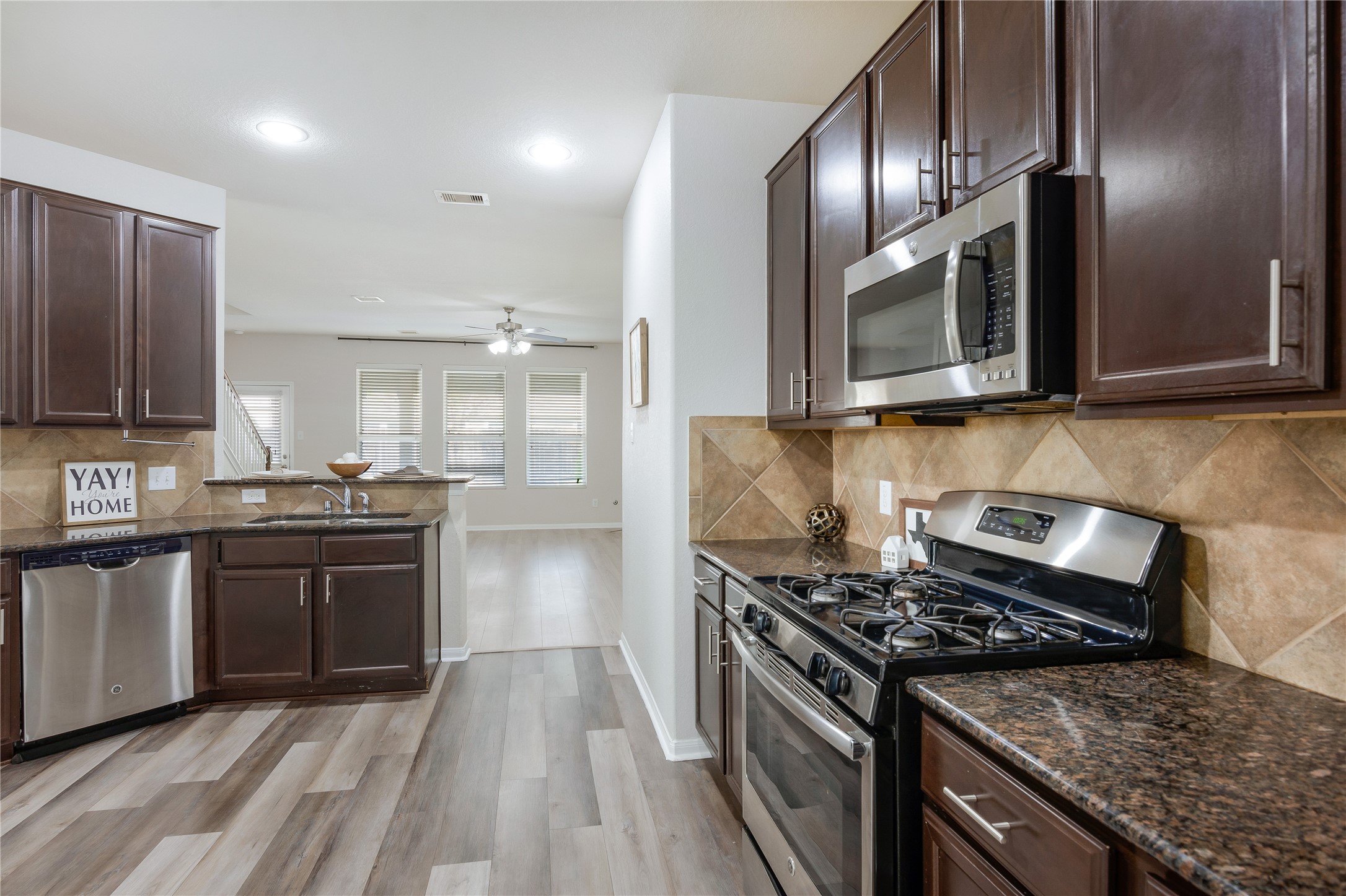 15007 Holland Grove Court Cypress, TX 77433 - Photo 6 of 28 a kitchen with stainless steel appliances granite countertop a stove top oven a sink dishwasher and microwave oven with cabinets
