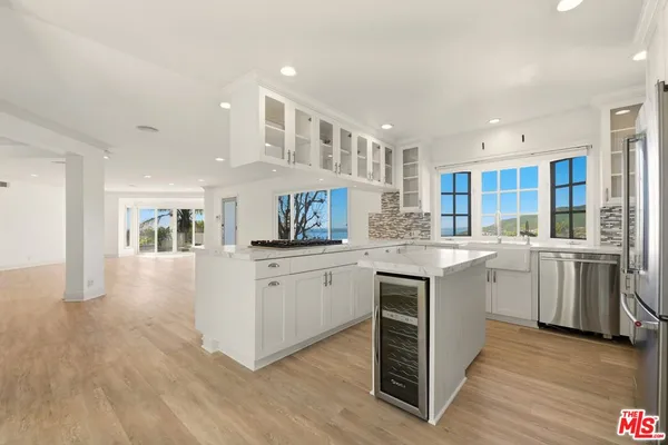 a kitchen with white cabinets and wooden floor