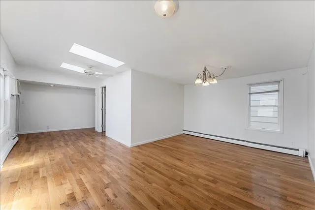 an empty room with wooden floor chandelier fan and windows