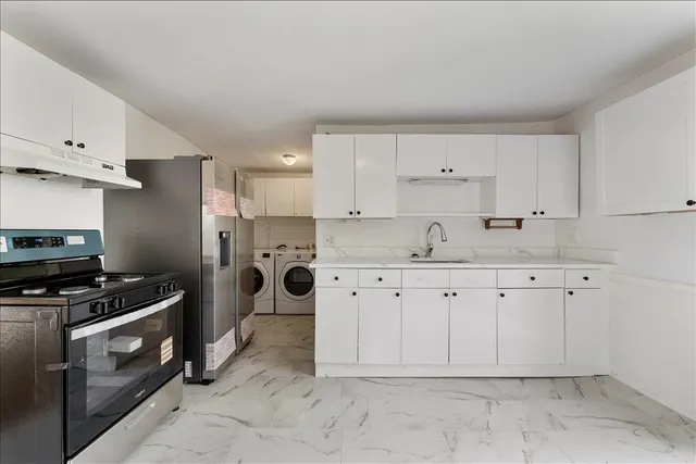 a kitchen with stainless steel appliances a stove a sink and white cabinets