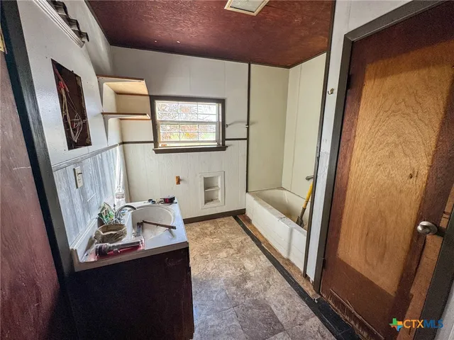an empty room with windows fireplace and a ceiling fan
