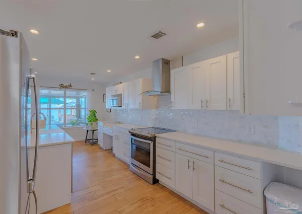 a kitchen with white cabinets and wooden floor