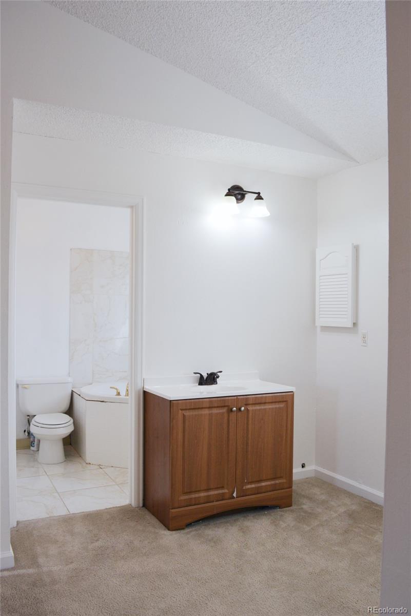 2087 South Quintero Street Aurora, CO 80013 - Photo 17 of 34 a bathroom with a toilet a sink and a mirror