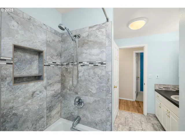 a bathroom with a granite countertop sink a shower and a bathtub