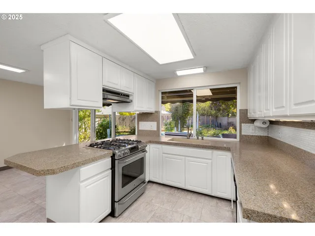 a kitchen with stainless steel appliances granite countertop a stove a sink and a microwave