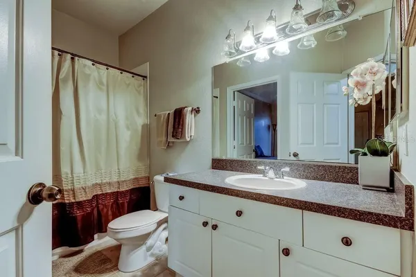 a bathroom with a granite countertop sink vanity mirror and toilet