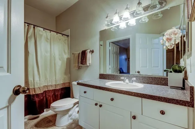 a bathroom with a granite countertop sink vanity mirror and toilet