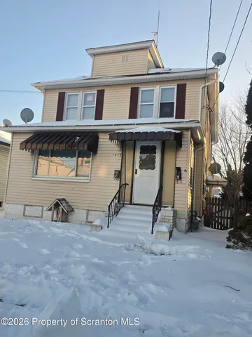 a view of a white house with large windows and a park