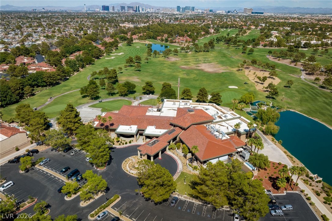 20 Innisbrook Avenue Las Vegas, NV 89113 - Photo 30 of 39 An aerial panorama reveals a golf course, adjacent clubhouse, and a sparkling lake, with cityscapes in the distance.