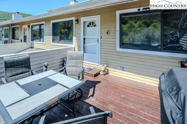 a roof deck with a dining table and chairs with wooden floor