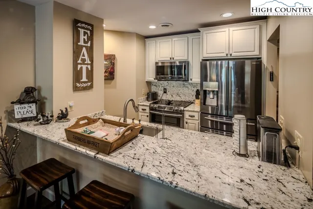 a kitchen with stainless steel appliances granite countertop a sink refrigerator and cabinets