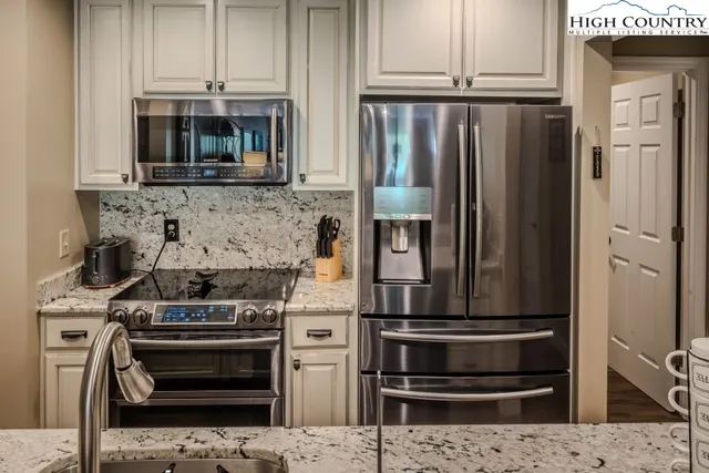 a kitchen with stainless steel appliances kitchen island granite countertop a stove and a refrigerator
