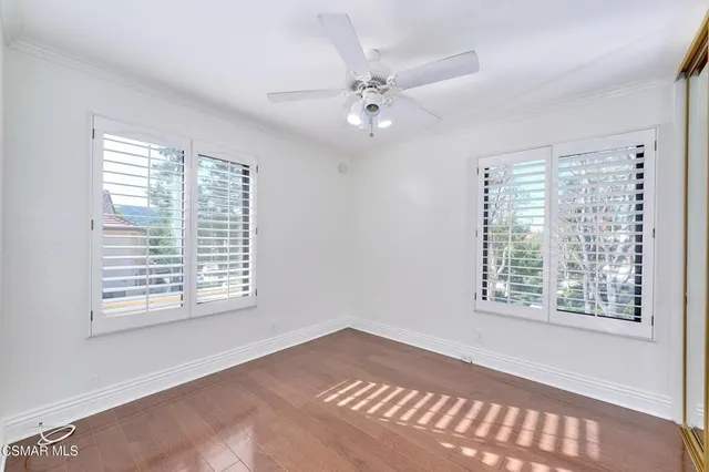 an empty room with windows and ceiling fan