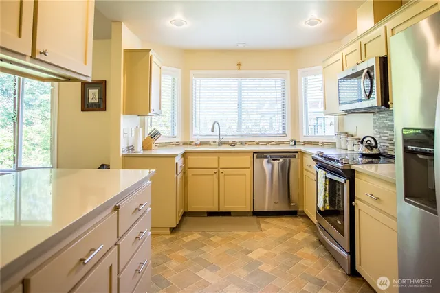 a kitchen with stainless steel appliances granite countertop a stove a sink dishwasher and a refrigerator