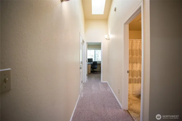 a view of a hallway with wooden floor and a bathroom