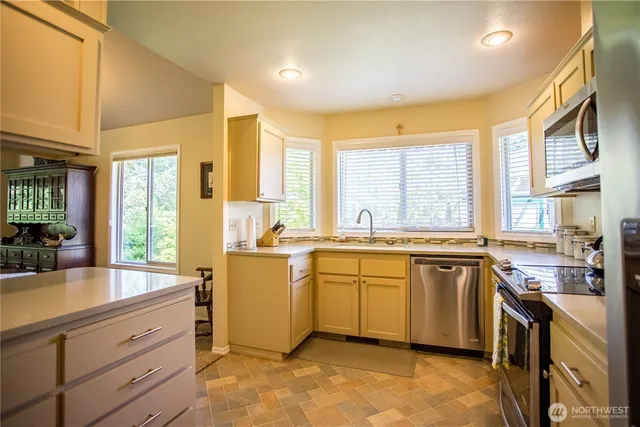 a large kitchen with kitchen island granite countertop a large counter top space a sink stainless steel appliances and cabinets