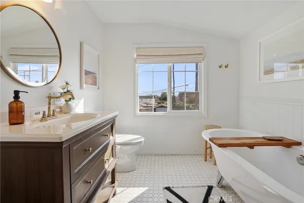 a bathroom with a sink a mirror a toilet and a window