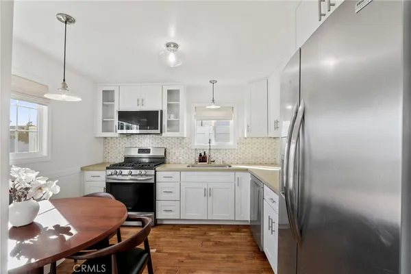 a kitchen with stainless steel appliances granite countertop a refrigerator a sink dishwasher a stove with white cabinets