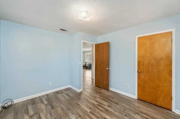 a view of an empty room with wooden floor and closet