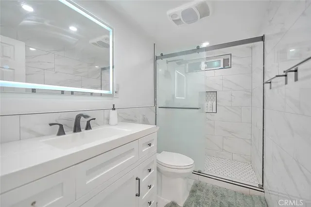 a bathroom with a toilet a sink a mirror and shower