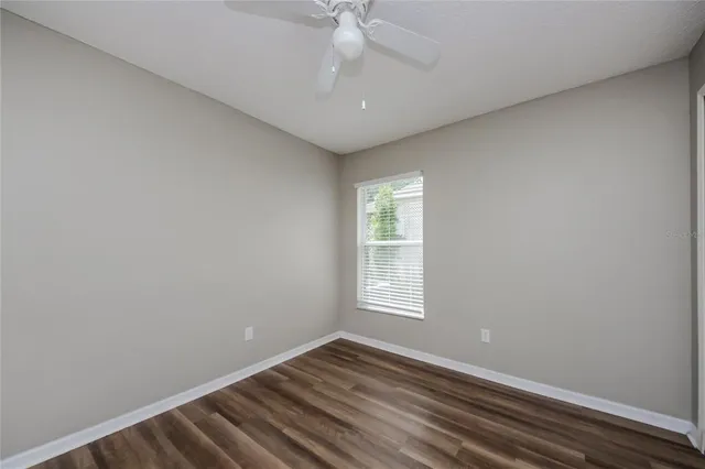 an empty room with windows and ceiling fan