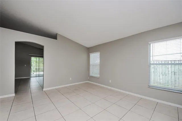 a view of an empty room with window and chandelier fan