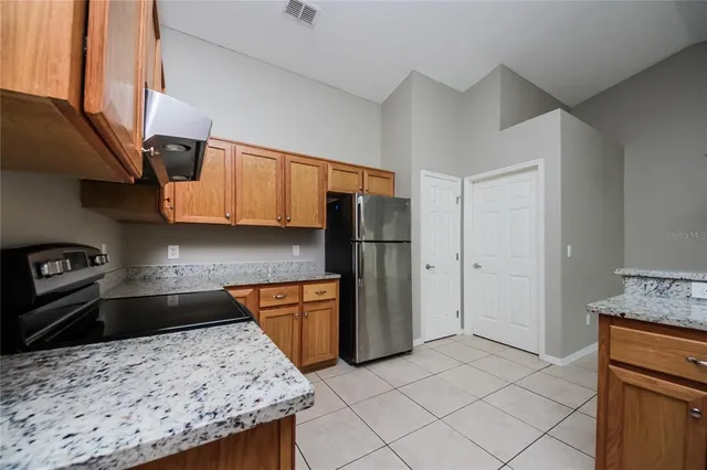 a kitchen with granite countertop a refrigerator and a stove top oven