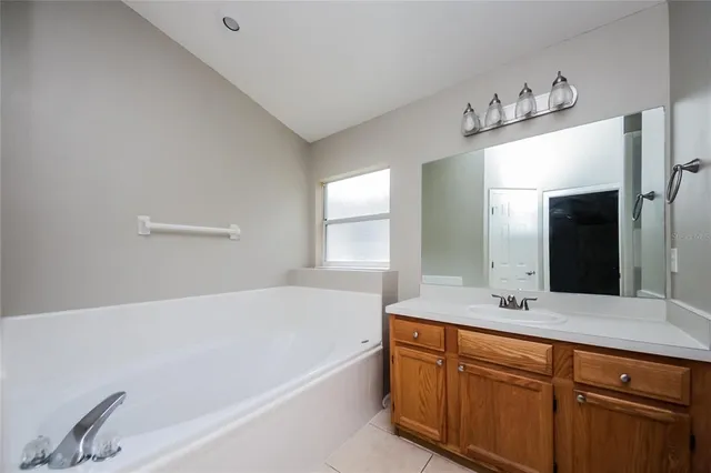 a bathroom with a bathtub a double vanity sink and mirror