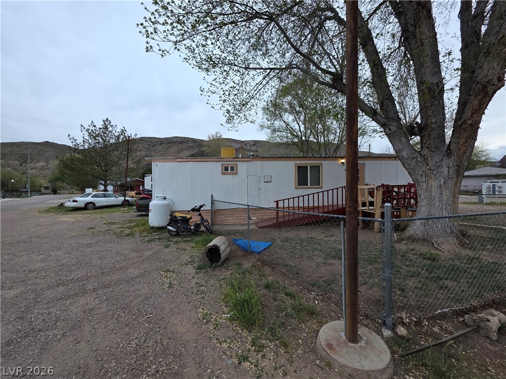 101 Ada Street, Unit 12 Caliente, NV 89008 - Photo 4 of 14 A well-maintained single-story residence with a practical ramp entry, set against a backdrop of rolling hills.