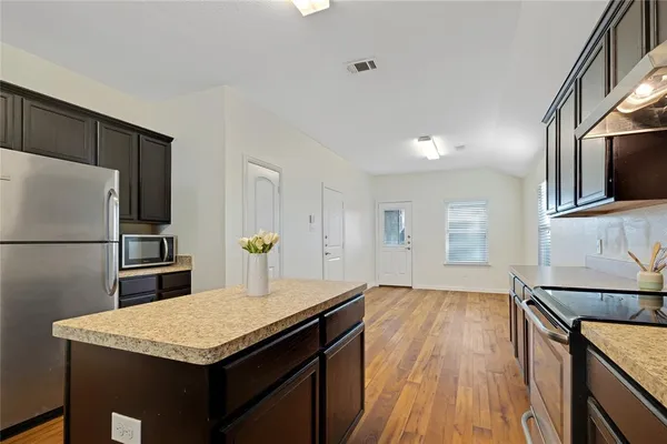 a kitchen with a sink a microwave a refrigerator and wooden floor