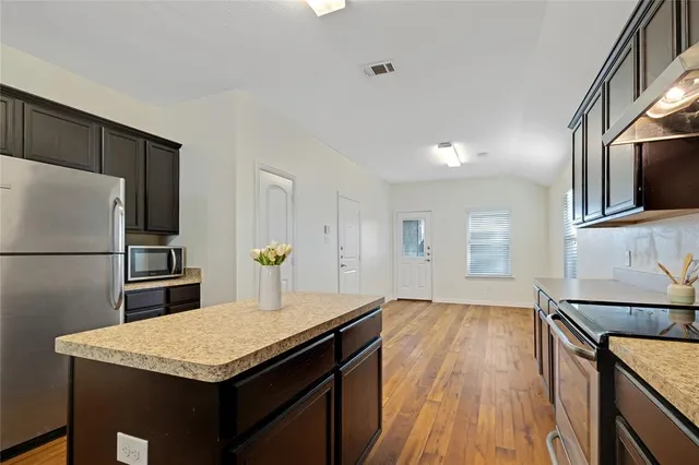 a kitchen with a sink a microwave a refrigerator and wooden floor