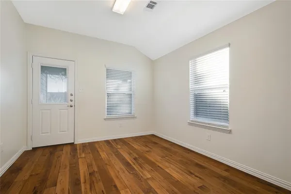 an empty room with wooden floor and windows