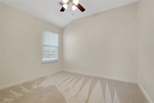 an empty room with a chandelier fan and windows