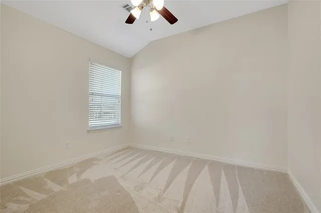 an empty room with a chandelier fan and windows