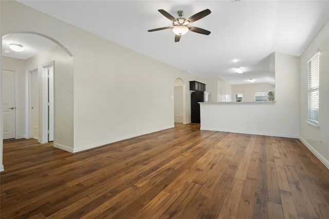 a view of empty room with wooden floor and ceiling fan