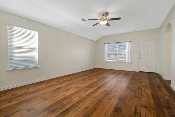 a view of empty room with wooden floor and fan