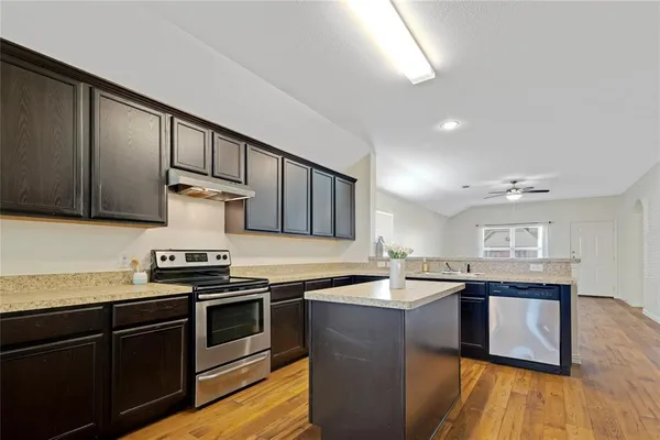 a kitchen with stainless steel appliances granite countertop a sink a stove and a wooden floors