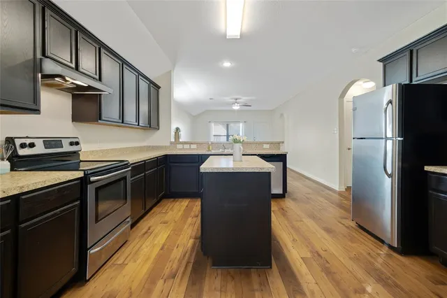 a kitchen with stainless steel appliances granite countertop hardwood floor sink stove and wooden floor